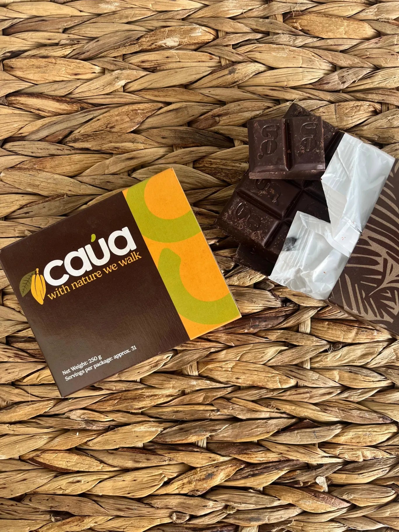 Caja Ceremonial de CAÚA sobre un tejido artesanal junto a la tableta de cacao 100% sin envoltorio